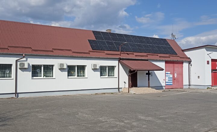 Budynek remizy Ochotniczej Straży Pożarnej z czerwonymi bramami garażowymi