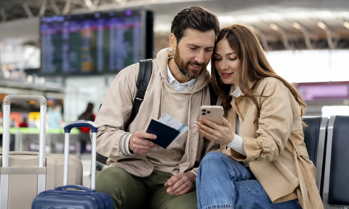 Para na lotnisku sprawdza telefon i dokumenty podróży