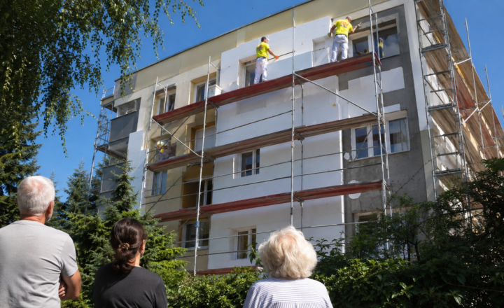 Robotnicy na rusztowaniach docieplają blok mieszkalny