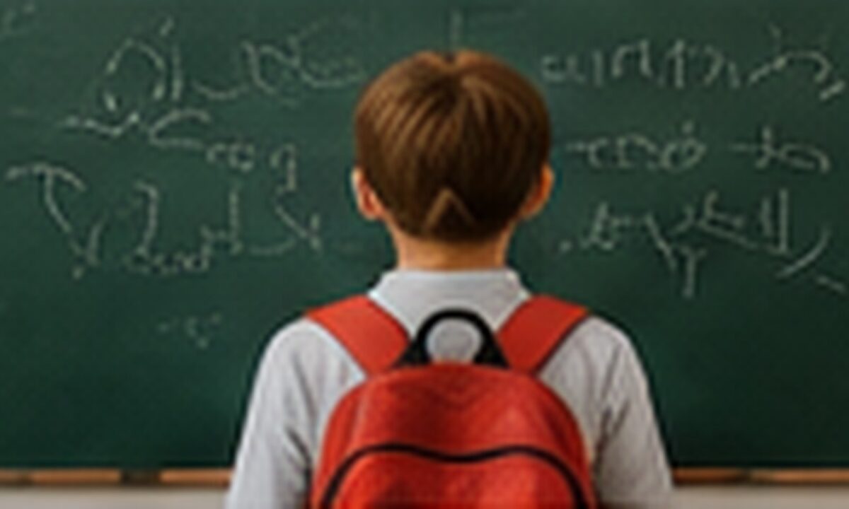 Uczeń z plecakiem przy tablicy szkolnej