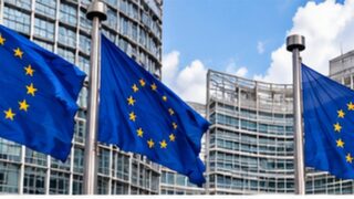 Flagi Unii Europejskiej na tle gmachu instytucji europejskich