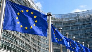 Flagi Unii Europejskiej przed instytucją w Brukseli