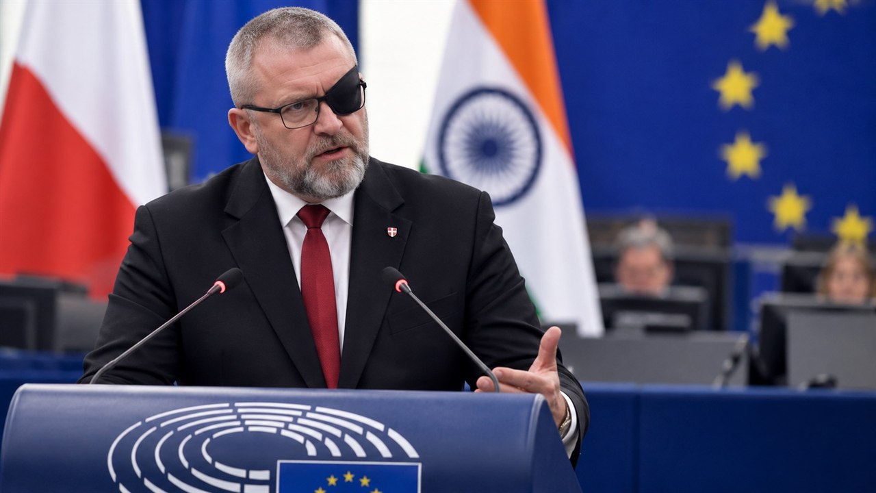 Ilustracja redakcyjna przedstawiająca Grzegorza Brauna przy mównicy na tle flag Polski, Indii i Unii Europejskiej