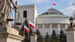 Gmach Sejmu RP z symbolem sprawiedliwości i polskimi flagami