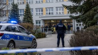 Budynek szkoły z policyjną interwencją i służbami przy wejściu