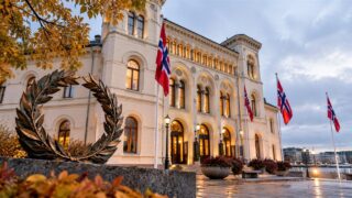 Fotorealistyczna ilustracja reprezentacyjnego budynku z norweskimi flagami i laurowym wieńcem