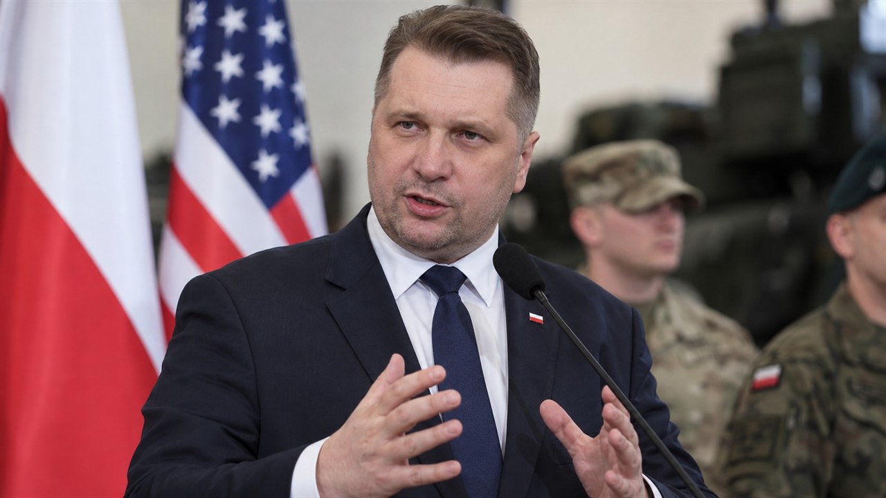 Przemysław Czarnek podczas wystąpienia na tle flag Polski i USA