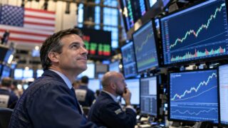 Maklerzy i ekrany z rosnącymi wykresami na Wall Street