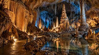 Wnętrze oświetlonej jaskini z licznymi naciekami, stalaktytami i stalagmitami; ilustracja tematu Jaskini Niedźwiedziej