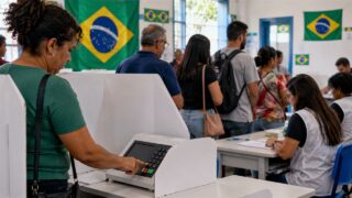 Wyborcy głosują przy elektronicznych urnach w lokalu z brazylijskimi flagami