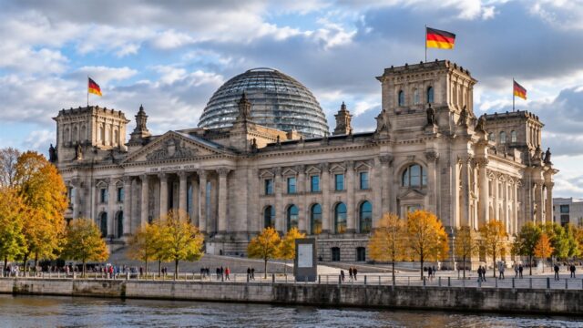Reichstag w Berlinie ze szklaną kopułą i niemieckimi flagami