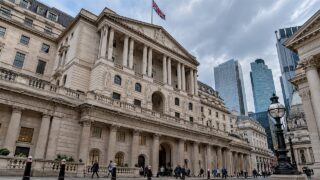 Symbol Banku Anglii na kamiennej fasadzie i centrum finansowe Londynu